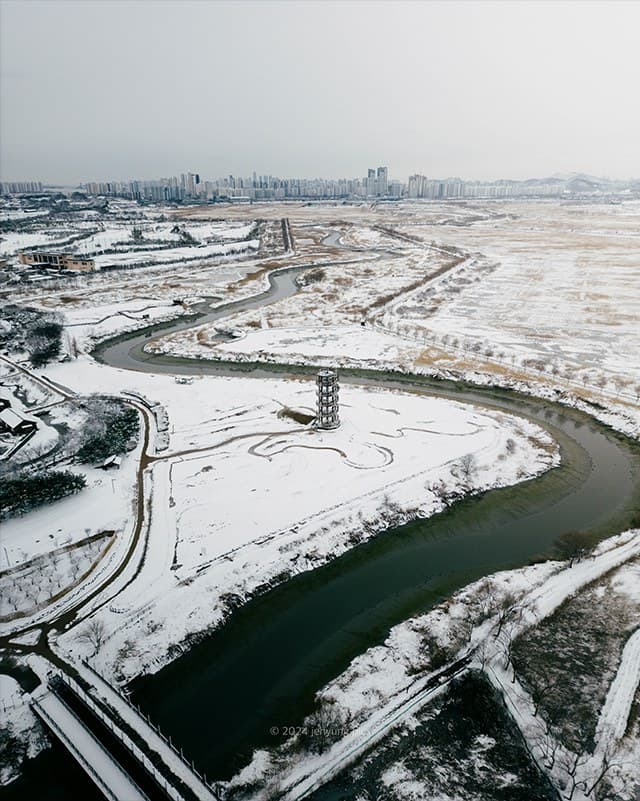 Aerial view of Siheung Gaetgol under snow with a dark river cutting through white fields