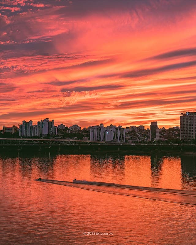 Blazing sunset over the Han River at Banpo Bridge with a single jet ski trailing across the water