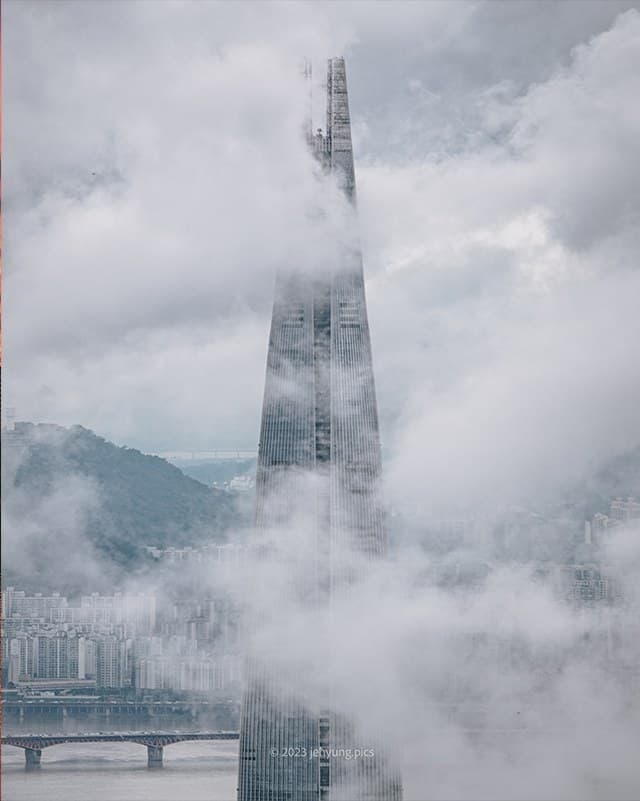 Lotte World Tower piercing through low clouds above Seoul